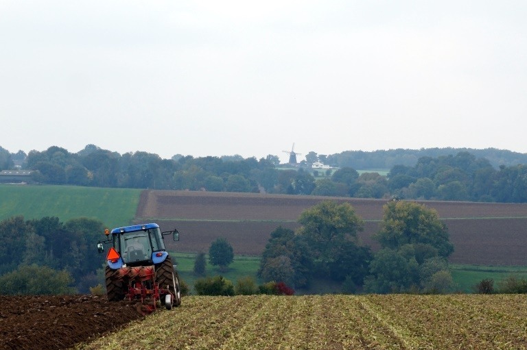 Tractor plowing with a view of the windmill on the Vrouweheide
